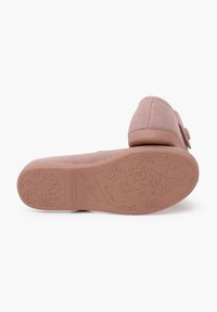 Zapatilla rosa con una parte superior de punto texturizado, puntera redondeada y una suela de goma con un patrón floral. Cuenta con un detalle de botón decorativo.