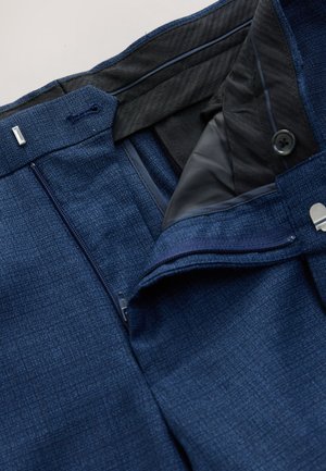 Marineblaue Hose aus strukturiertem Stoff mit Knopf- und Reißverschluss, schwarzem Innenfutter und zusätzlichen Taschen für Funktionalität.