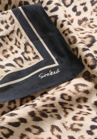 Leopardprint tørklæde i beige og brunt stof med en sort kant og en hvid streg; "Soaked" mærke syet nær kanten.