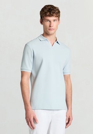 Hellblaues Polohemd mit kurzen Ärmeln und strukturierter Oberfläche, ausgestattet mit einem V-förmigen Kragen und weißen Akzenten am Kragen und den Ärmeln.