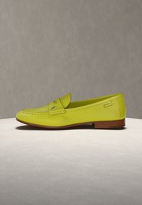 Κίτρινο δερμάτινο μοκασίνι με ξύλινη σόλα, ραφές λεπτομέρειες και μικρή ετικέτα "Polo" στο πλάι, εκτεθειμένο σε ανοιχτή επιφάνεια.