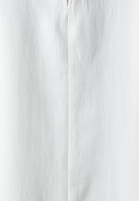Weißes Kleidungsstück mit einer glatten, leicht strukturierten Oberfläche und einem zentralen Reißverschluss. Schlichtes Design mit klaren Linien, ohne sichtbare Muster oder Verzierungen.