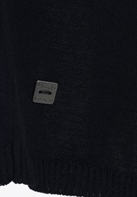 Maglione nero in maglia con orlo e polsini a costine, dotato di una piccola etichetta del marchio in argento embosso con "Manila Grace" attaccata di lato.