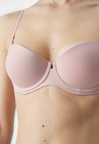 Reggiseno imbottito rosa chiaro con ferretto, spalline regolabili e una texture sottile. Tessuto morbido con un design senza cuciture.