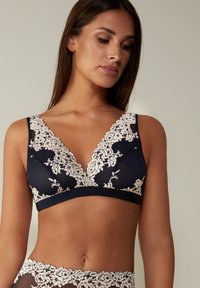 Navyblauer Spitzen-Bralette mit tiefem V-Ausschnitt, das an den Rändern mit kunstvollen Blumenmustern verziert ist und aus einem strukturierten Stoff besteht. Weich, ohne Polsterung.