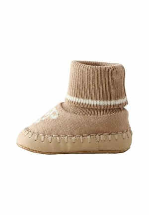 Knitted beige infant booties with a ribbed ankle, soft leather sole, and decorative white stitching along the edge.