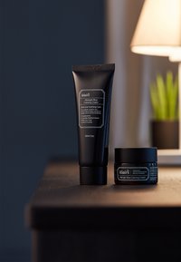 La crème apaisante Midnight Blue de Klair's dans un tube et un pot noir mat. Les deux présentent un texte blanc avec un design minimaliste. Tube de 60 ml, pot de 50 ml.