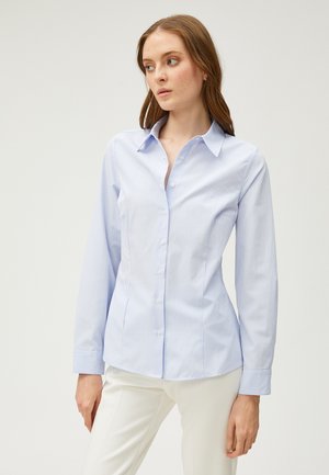 Chemise à rayures bleu clair avec un col classique, des manches longues et une coupe ajustée. Fabriquée en tissu lisse avec une texture subtile.