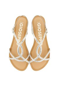 Sandalias planas plateadas con correas trenzadas y un diseño geométrico. Plantilla marrón con el nombre de la marca impreso. Hebilla ajustable para un mejor ajuste.