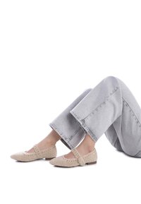 Bailarinas texturizadas beige con punta afilada, que cuentan con una correa y cuentas decorativas, combinadas con pantalones de mezclilla de pierna ancha en gris claro.