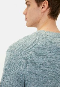 Melange knit sweater in shades of blue and green with textured detailing on shoulders and ribbed neckline. Close-fitting design.