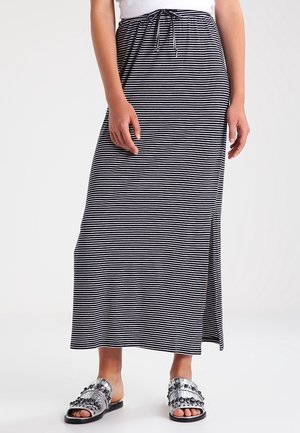 Maxinederdel med sorte og hvide striber og bindebånd i taljen, med en slidser i siden. Kombineret med sølvfarvede slides med pynt.