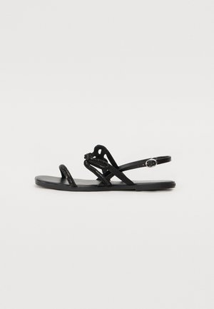 Sandalha preta plana com tiras finas, apresentando brilhos, uma tira ajustável no tornozelo e um design de sola lisa.