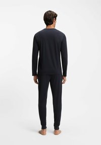 Długie rękawy i spodnie w ciemnoszarym kolorze, wykonane z miękkiej tkaniny, oferujące luźne dopasowanie oraz ściągacze przy kostkach i nadgarstkach.