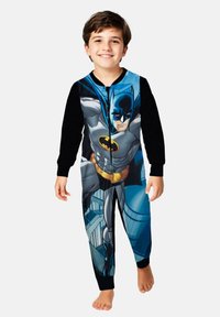 Tutina a tema Batman con design metà nero e metà stampato, caratterizzata da grafiche da supereroe, chiusura con zip e tessuto morbido e liscio.