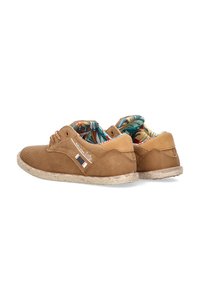 Zapatos de ante marrón con diseño perforado, acentos en beige y una suela de fibra natural texturizada. El interior presenta un patrón de hojas tropicales.