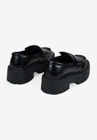 Zapatos de plataforma de cuero negro con punta redonda, suela de goma gruesa y detalle de costura. Presentan un acabado suave y una ligera curvatura ascendente.