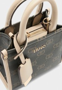 Stilvolle Handtasche mit einem dunkel gemusterten Äußeren, hellen Griffen, einem goldenen Reißverschluss und einem Logo, das eine Kombination aus Eleganz und Funktionalität zeigt.