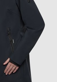 Mörk marinblå vattentät jacka med en slät yta, slim fit och sidoficka med dragkedja, samt mjukt innerfoder vid ärmsluten för bättre isolering.