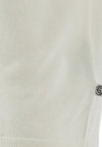 Nahaufnahme von weißem Stoff mit einem kleinen Etikett, das ein schwarzes kreisförmiges Symbol am rechten Rand zeigt.