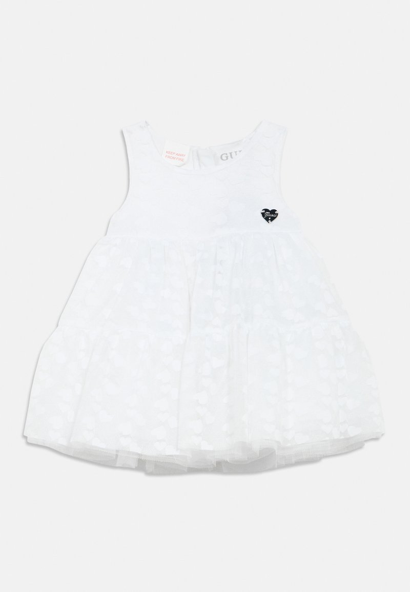 Robe blanche sans manches, ornée d'un motif cœur texturé avec un accent cœur noir. Des couches de tulle forment une jupe évasée.