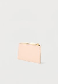 Porte-monnaie rectangulaire en cuir rose pâle avec deux compartiments zippés dorés et tirettes blanches sur un fond blanc uni.