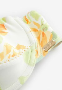 Kvetinový bralet s mäkkou látkou v bielej, oranžovej a zelenej farbe. Obsahuje čipkovaný lem a malú zlatú značku na boku.