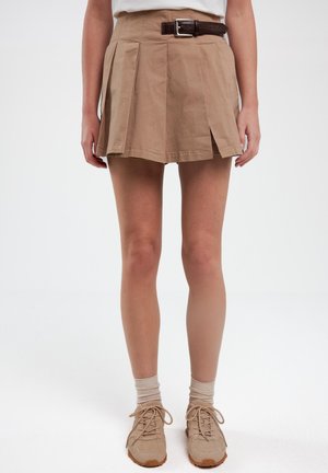 Beige Baumwoll-Faltenrock mit einem braunen Ledergürtel. Das Design zeichnet sich durch eine taillierte Passform und eine ausgestellte Form aus, mit seitlichen Schlitzen für mehr Flexibilität.