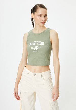Grøn ribbet crop top med en rund udskæring, der har hvid tekst "CHAMPIONS NEW YORK 1986 BROOKLYN" og en tætsiddende design.