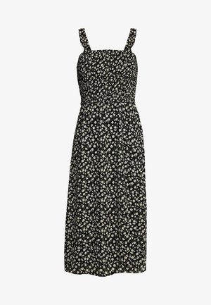 Robe noire avec un corsage smocké, des bretelles fines et un motif floral blanc et vert, descendant jusqu'aux genoux.