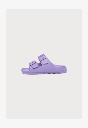 Sandale slide violet lilas avec deux brides réglables à boucle et semelle texturée, vue de côté sur fond blanc.