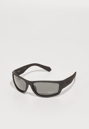 Ochelari de soare din plastic negru, cu lentile gri închis. Design elegant, cu formă înfășurată, brațe curbate și branding discret pe tâmpla.