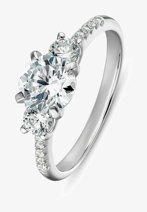 Bague trois pierres mettant en valeur un grand diamant rond central et deux plus petits diamants ronds. Monture en or blanc avec de petites accents en diamant.