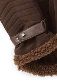 Bruine suède handschoen met een gestikt patroon, een bruine leren band met een drukknoopsluiting en een zachte, gestructureerde bruine voering.