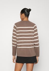 Hnědý a krémový pruhovaný svetr s dlouhými rukávy a kulatým výstřihem, vyrobený z texturované tkaniny, s rovnými lemy a raglánovými švy.