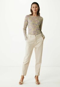 Dlouhý rukáv top v jemném, lila a žlutém květinovém vzoru; spárován s krémovými kalhotami se šněrovacími detaily na lemu a zlatými sandály na podpatku.