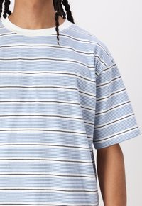 T-shirt à manches courtes rayé en blanc, bleu et marine. Avec un col rond et un tissu doux aux lignes horizontales. Coupe légèrement ample.