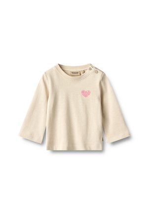 T-shirt bébé beige à manches longues avec deux boutons aux épaules et un petit cœur rose avec le texte "Wild Heart" sur la poitrine.