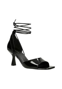 Schwarze Sandale aus Lackleder mit offenem Zehenbereich, quadratischer Spitze, mittelhohem geschwungenem Absatz und dünnen Riemchen, die um den Knöchel gewickelt sind.