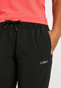 Pantalones deportivos negros con cinturilla elástica y cordón, que presentan bolsillos laterales y un logo de CMP en plata en el muslo izquierdo.