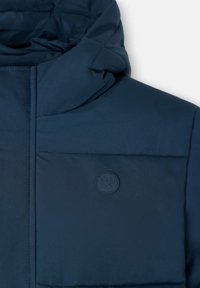 Chaqueta acolchada azul marino con capucha, que cuenta con una sección superior texturizada, un bolsillo en el pecho destacado y un logo sutil en el bolsillo.
