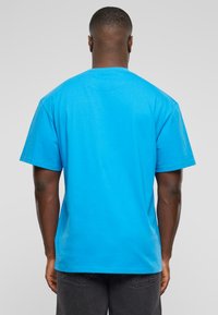 Short-sleeve t-shirt in bright blue cotton, featuring a crew neck and a relaxed fit. The back view shows a smooth texture and simple design.
