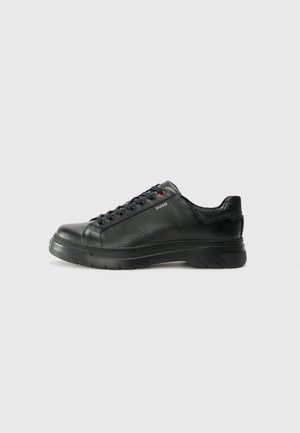 Black leather sneaker with textured upper, padded collar, and red logo detail. Features a thick rubber sole with distinct tread pattern.