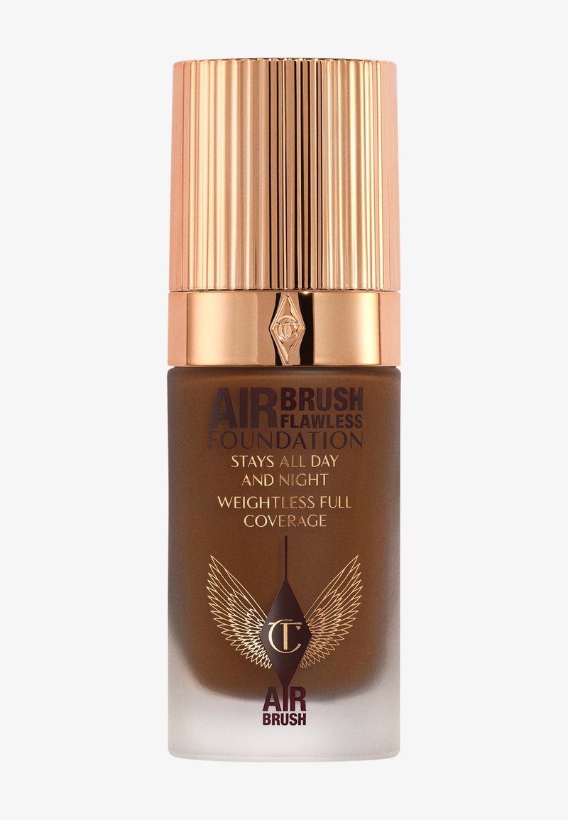 Bottiglia di fondotinta in vetro marrone con tappo dorato rigato. Presenta testo in rilievo dorato e disegni di ali, etichettato "Fondotinta Airbrush Flawless."