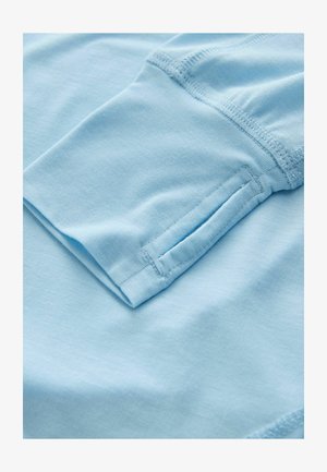 Material de bumbac albastru deschis cu textură moale, având o mânecă pliată și cusături atent realizate, care prezintă un luciu subtil.