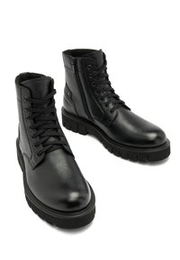 Czarne skórzane botki za kostkę mają teksturowane wykończenie, okrągły czubek, sznurowanie z przodu, zamek błyskawiczny z boku oraz masywną gumową podeszwę dla stabilności.