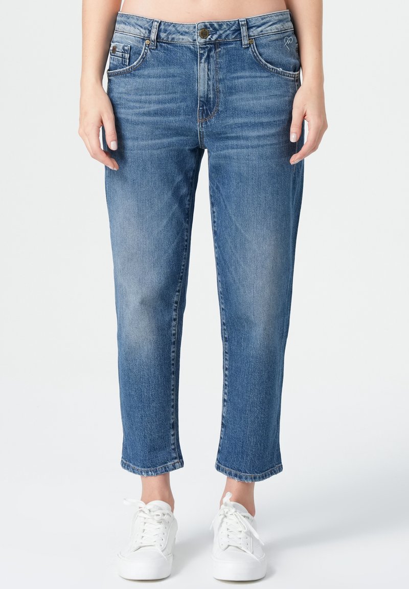 Helles blaues Denim-Jeans mit geradem, verkürztem Schnitt. Mit Fronttaschen, Gürtelschlaufen und einer ausgeblichenen Wasche. Getragen mit weißen Sneakers.