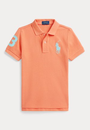 Korallo-pomarańczowa koszulka polo z krótkim rękawem, z jasnoniebieskim haftowanym logo gracza polo na piersi oraz numerem 3 na prawym rękawie.