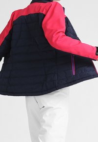 Padded jacket z granatowym korpusem i jaskraworóżowymi rękawami, z bocznymi kieszeniami na zamek i kontrastowymi szwami, zaprojektowany z myślą o ciepłu i swobodzie ruchów.