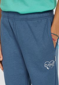 Pantaloni tuta blu realizzati in un tessuto morbido, con cintura elastica, tasche laterali e un logo O'Neill bianco con un design a cuore sulla gamba.